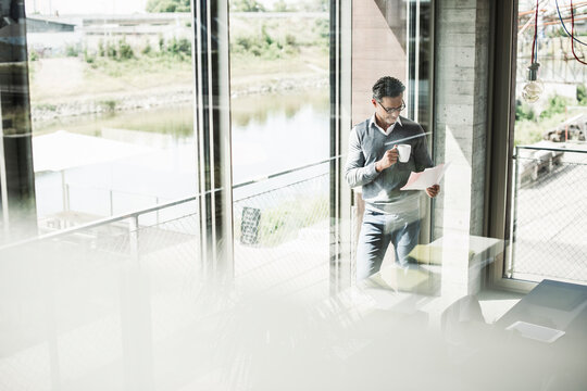 Businessman with coffee mug looking at documents in an office