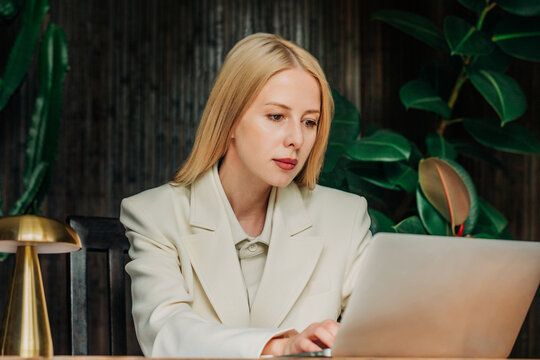 Businesswoman in a white suit works on a laptop in a modern office