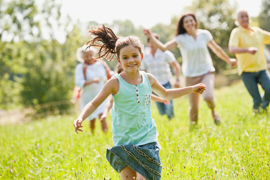 Germany, Bavaria, Family running together in grass at picnic
