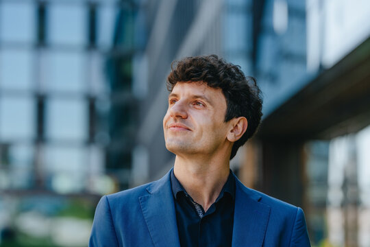 A dreaming businessman looks up at a modern building
