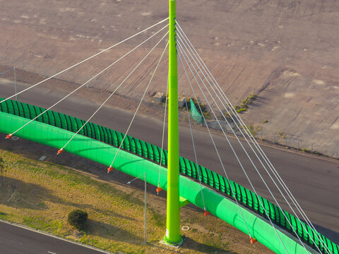 Aerial view of a bright green cycling bridge alongside a highway