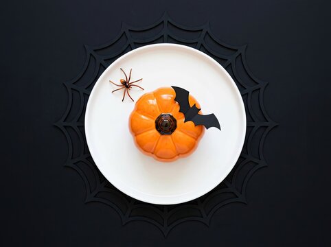 Pumpkin mousse dessert on a spiderweb plate setup ideal for Halloween dining promotions symbolizing festive indulgence and spooky fun