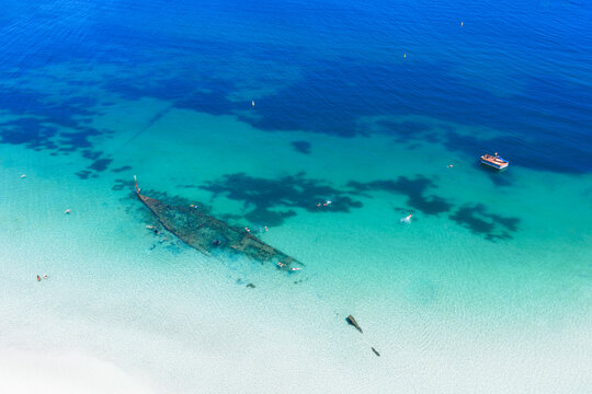 Aerial of shipwreck can be seen in the crystal clear ocean near local beach