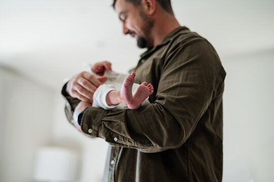 Father carrying newborn baby girl inside home