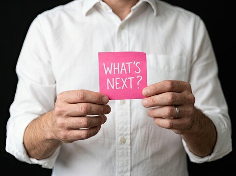 Man holding pink note saying WHATS NEXT suitable for career and business media representing strategic decision making and future direction