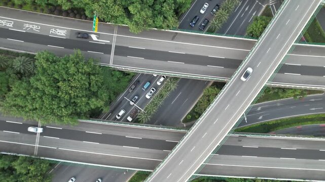 Aerial top view of cars on multi level highway interchange with surrounding greenery