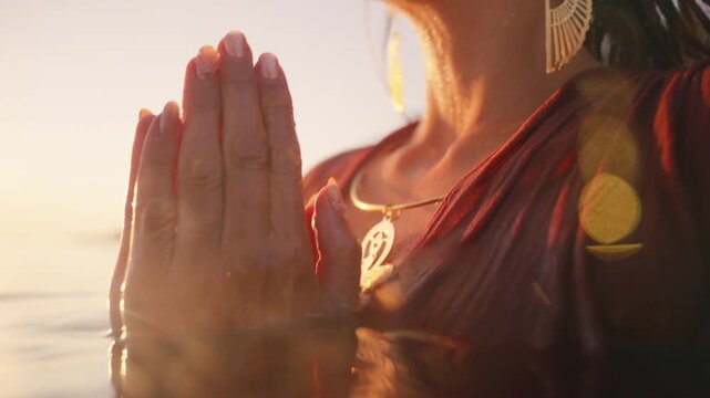 Underwater close up of an arm reaching toward the surface, a gold bracelet and ankh pendant catching the light.