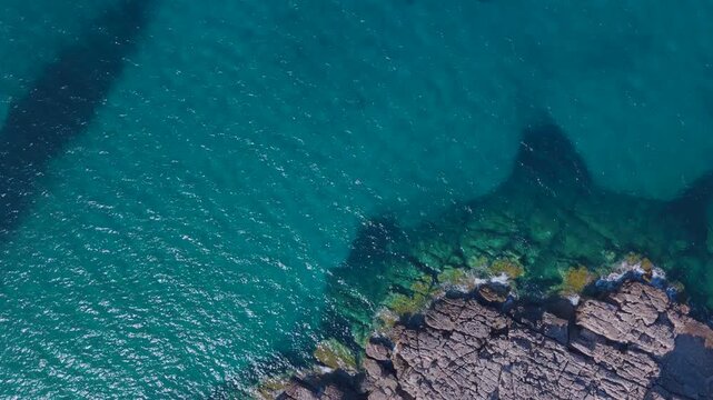 Top Down Aerial View of a Lone Swimmer in Turquoise Sea Beside Rocky Coast at Voidokilia, Greece