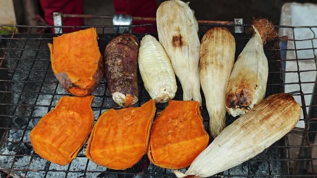 Grilled sweet potatoes and corn being roasted on a grill