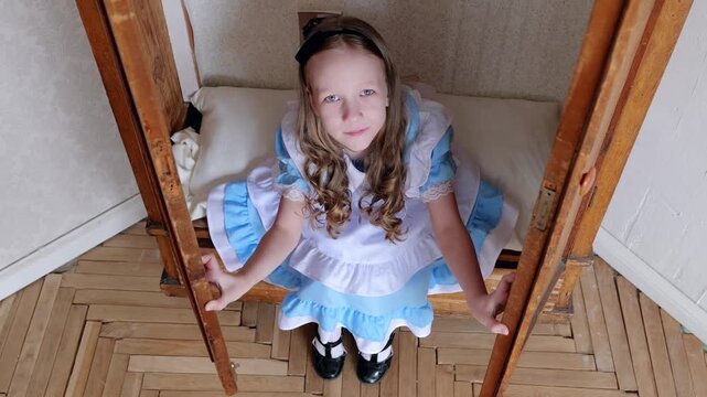 Overhead Girl Standing Inside Wardrobe Doorway Looking Up To Camera, Parquet Floor, Blue Dress, Hands On Doors, Confident Gaze, Playful Exploration, Home Interior, Cinematic Perspective