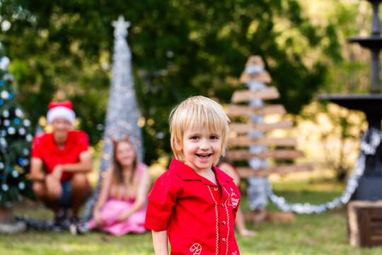 Preschooler boy portrait at Christmas with his family watching