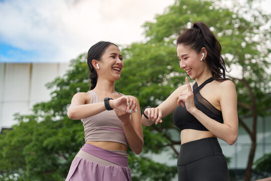 Asian women checking smartwatches outdoor for smart fitness tracking and technology