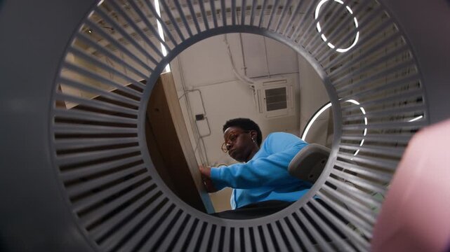 Young adult African American woman throwing crumpled paper into trash bin, captured from low angle inside basket. Footage is suitable for office waste or creative block concepts