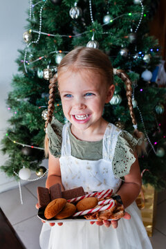Happy little girl with plate of candy canes and homemade ginger biscuits and tam tams