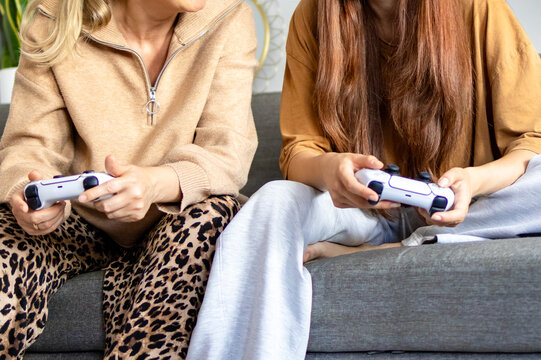 Two pairs of hands hold white game controllers side by side during shared video game session. Concept of generational gaming teamwork and synchronized hands on gameplay experience together.