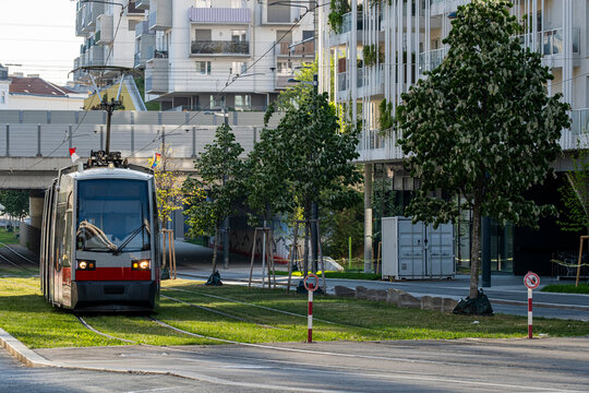 Modern tram in Vienna Austria travels beside landscaped tracks and contemporary buildings in a clean urban public transportation scene