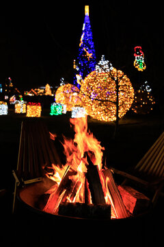 Bright lights and a fire burn in a festive setting at night during a holiday Christmas celebration