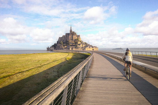 femme &agrave; v&eacute;lo, arrivant devant le Mont Saint Michel en Normandie