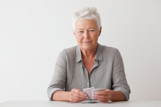Senior woman enjoying a card game while holding playing cards at a table in a cozy indoor setting showcasing leisure activities for older adults. Generative AI