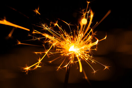 Sparkler glowing with sparks to celebrate new years eve with bokeh lights in background