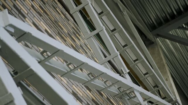 Steel truss structure mounted against decorative brick interior wall. Corrugated metal roofing sheets angled above industrial framing