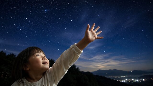 満天の星空を見上げ手を伸ばす、夢見る幼い女の子の夜景