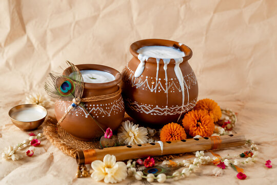 Traditional Janmashtami Still Life Setup Featuring Clay Pots Filled With Cream Peacock Feather Bamboo Flute Garland Of Fresh Marigold Flowers
