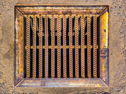 Rusty Metal Storm Drain Grate in Concrete