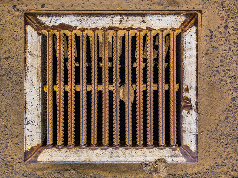Close-Up of Rusty Storm Drain Grate in Textured Concrete