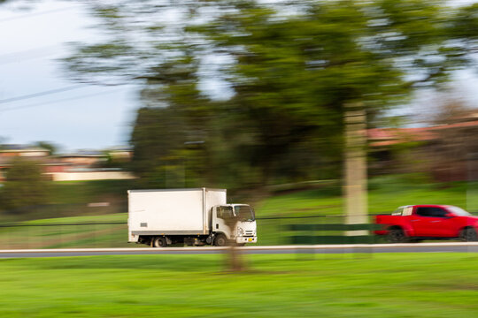 Panning shot capturing motion of truck driving along road transporting goods