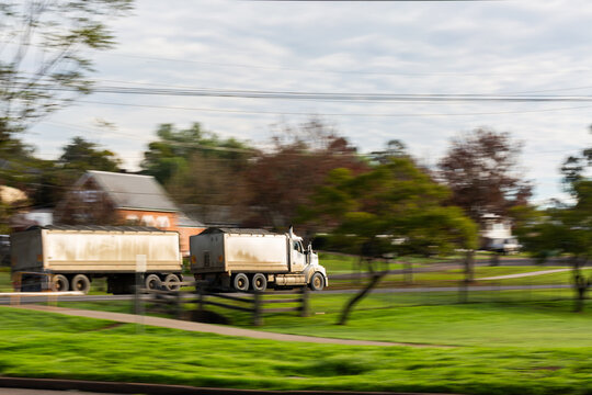 Panning shot capturing motion of truck driving along road transporting goods
