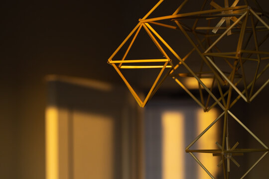Golden hour light illuminates a hanging geometric pagan decoration made of straw