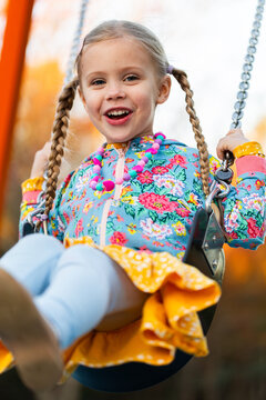 child playing on swing at park in colourful jumper