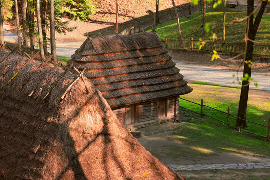 Traditional Eastern European village with thatched roof log houses in sunlight