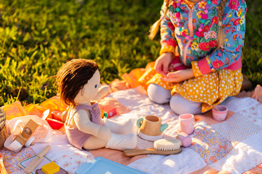 tea set toys and doll outdoors having a pretend picnic