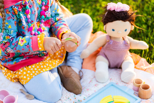 happy little girl playing with pretend wooden fruit food and doll