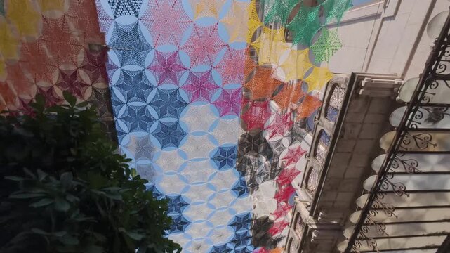Low angle view of colorful woven textiles hanging above streets in a Mexican city