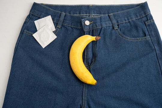 Banana with measuring tape and condom on jean trousers, penis health.