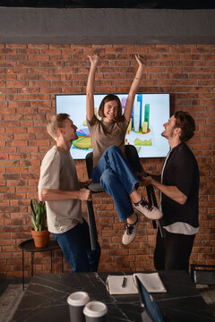 Excited team celebrating achievement in modern office setting with enthusiasm