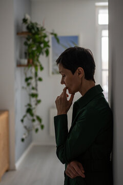 Nervous weary woman leaning against wall deep in thought in emotional numbness and anxiety. Mental struggle, inner conflict, bad news, psychological distress, emotional crisis, burden of problems