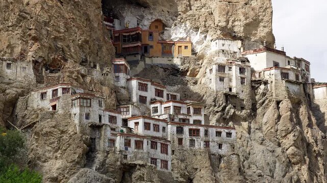 Zanskar, India : Static footage of bird flies around Phuktal gompa, cliffside monastery built in natural cave of Zanskar in Ladakh, India on cloudy day in the himalayas