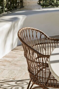 Closeup of woven wrought iron chair backing on a Spanish Revival patio with warm afternoon light casting intricate shadow patterns