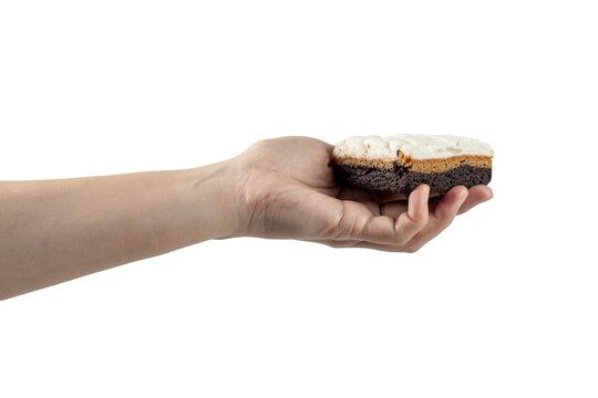 A brownie topped with marshmallows in hand against a transparent background.