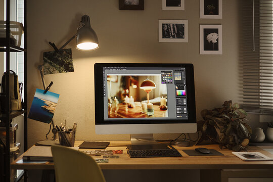 Desktop computer displaying photo editing software on wooden desk in home office, representing remote creative work. Image suitable for digital marketing and freelance business promotions