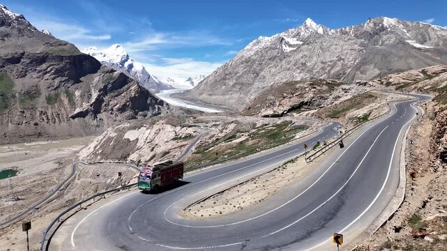 Zanskar, India : Tilt down and upward footage of truck passes mountain road in Pensi La, famous mountain pass in Zanskar of Ladakh, India with dramatic Drang drung glacier on sunny day in the Himalaya
