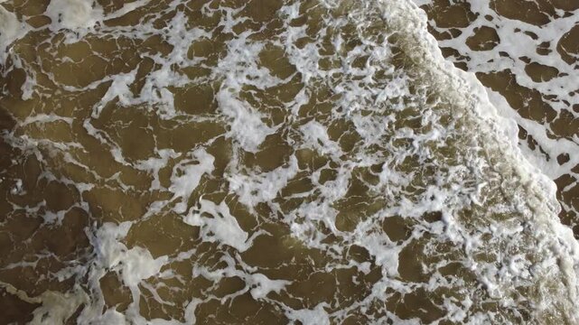 Waves rolling onto a beach seen from above