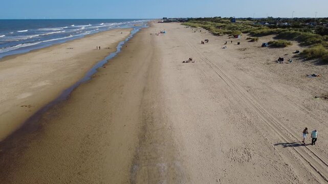 Drone shot looking along Mablethorpe beach in Lincolnshire, UK, a sandy beach beneath a blue sky