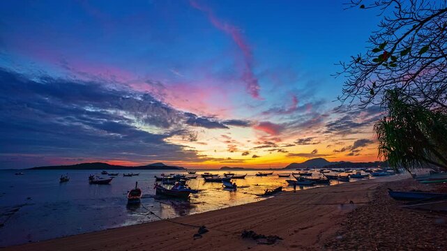 Time lapse Scenic tropical sunset with colorful clouds, island silhouette, and anchored boats on calm water. Ideal for travel, tourism, marine, and nature themed projects.