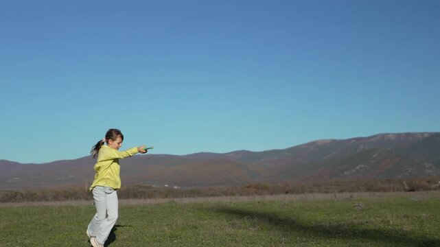 Juggling girl acrobatics, practicing diabolo sticks outdoors in mountain field on a bright sunny day.