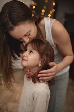 portrait of mother and daughter, real people, hugging in front of Christmas tree, celebrating Christmas. out of focus, moving with noise and scratches on the sensor, blurring. vibrant, emotional photo
